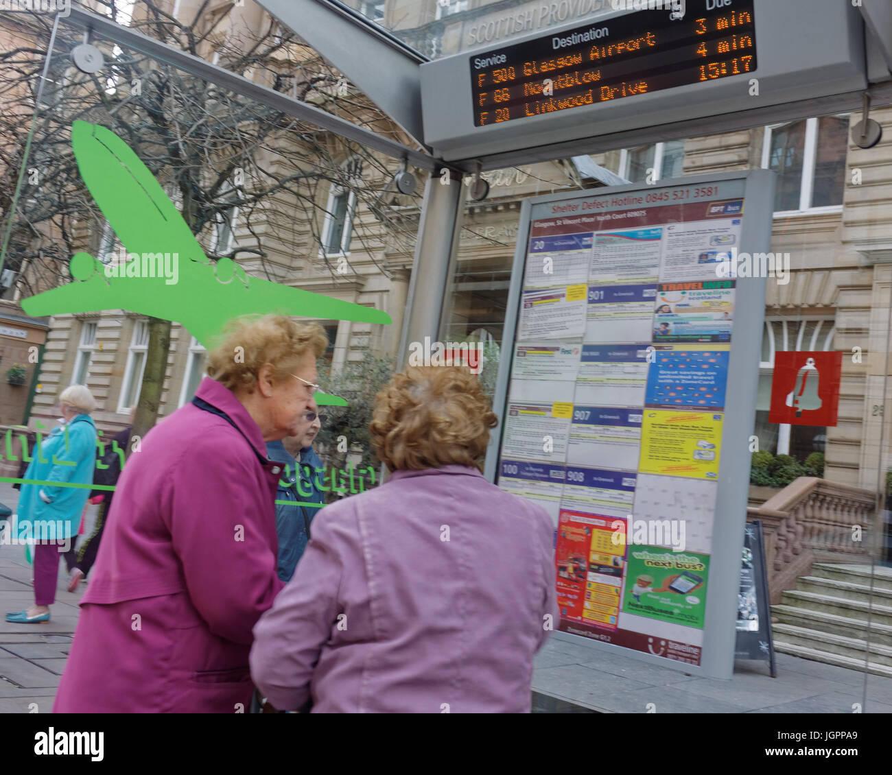 alte Damen Beratung Busfahrplan an einer Bushaltestelle mit Jet Flugzeug Aufkleber und Flughafen Businformationen über Scanner an Bord St Vincent Street Glasgow Schottland Stockfoto