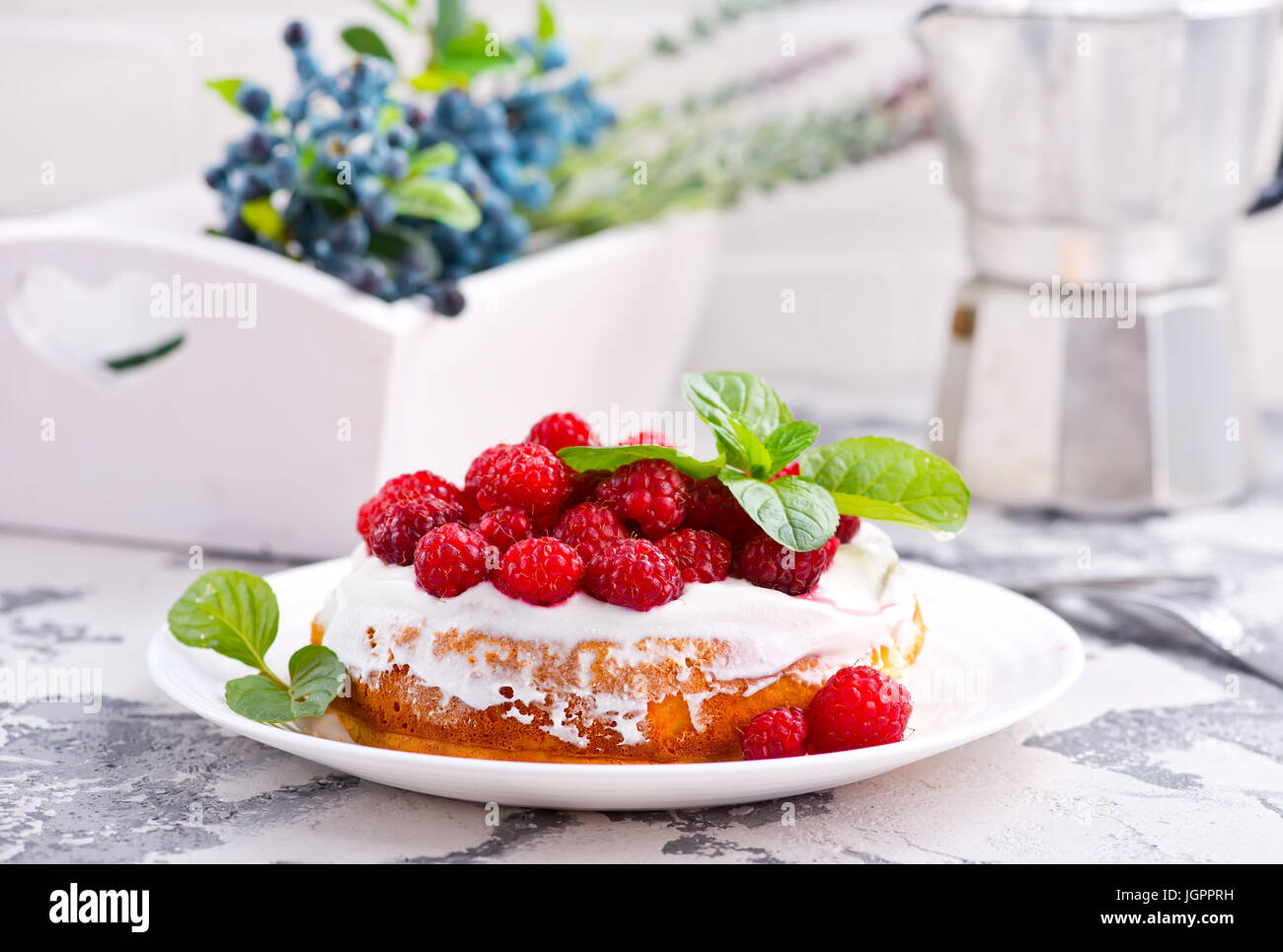 Kuchen mit Himbeeren und Sahne auf einem Tisch Stockfoto