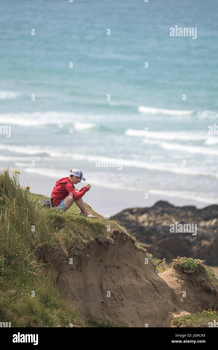 Eine junge Frau, die sich in der warmen Sonne auf der Landspitze in Newquay, Cornwall. Stockfoto