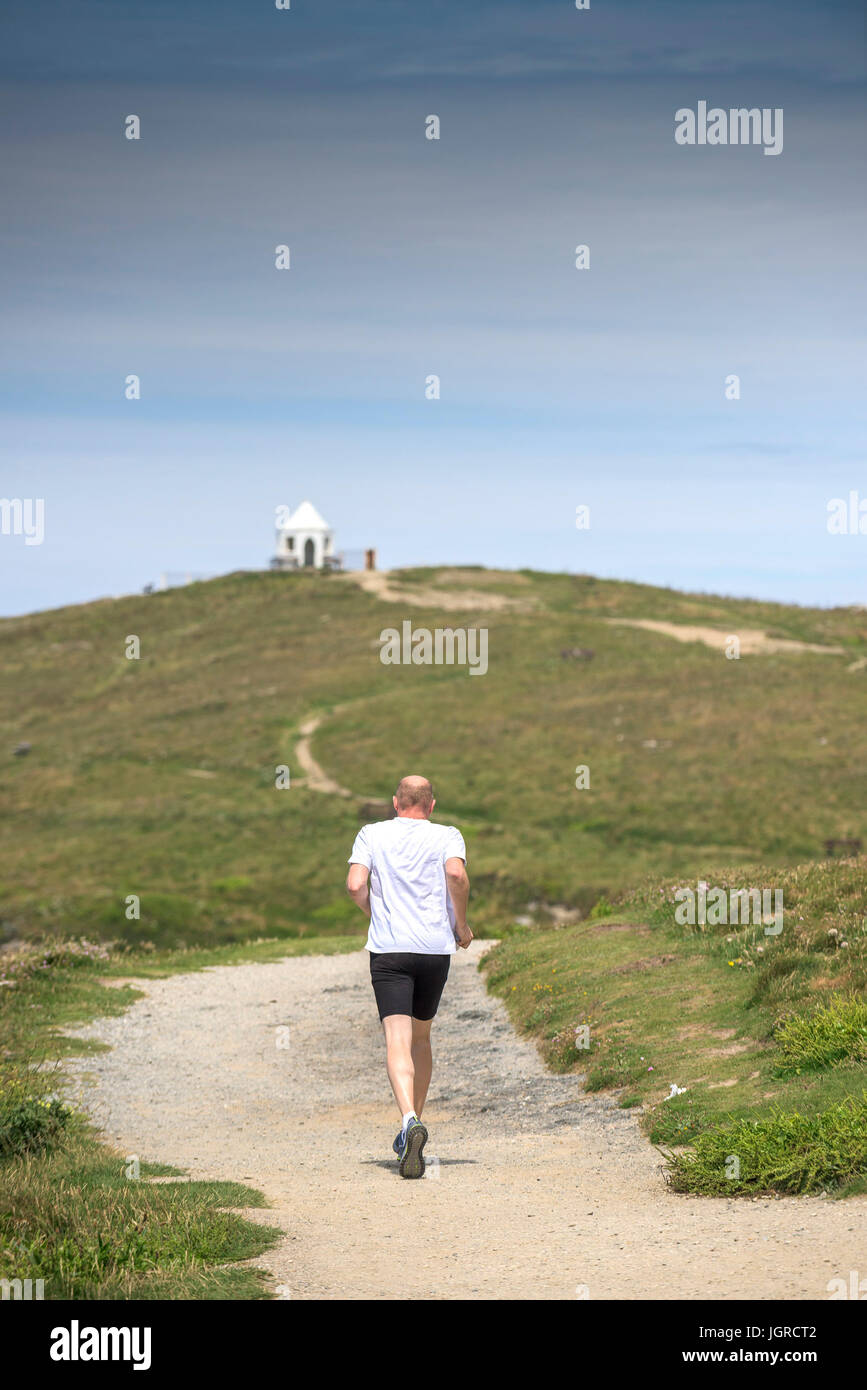 Ein Mann läuft entlang dem Wanderweg führt zu Towan Landzunge in Newquay, Cornwall. Stockfoto