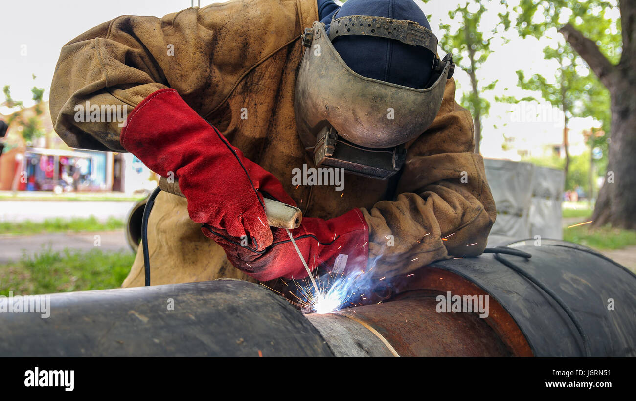 Rohr auf den Rohrleitungsbau Schweißen. Arbeiter mit Schutzmaske Schweißen Metall. Stockfoto
