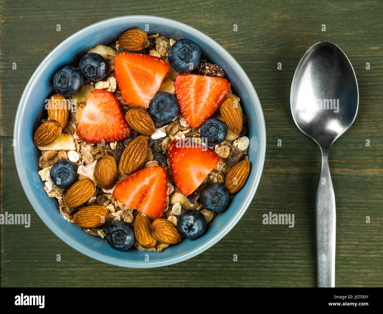 Frühstück Müsli Müsli mit Erdbeeren und Blaubeeren Obst vor einem grünen Hintergrund Stockfoto