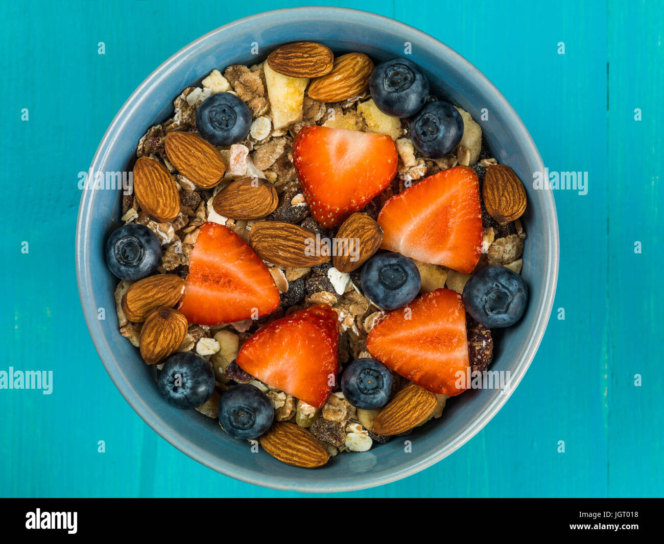 Frühstück Müsli Müsli mit Erdbeeren und Blaubeeren Obst vor einem blauen Hintergrund Stockfoto
