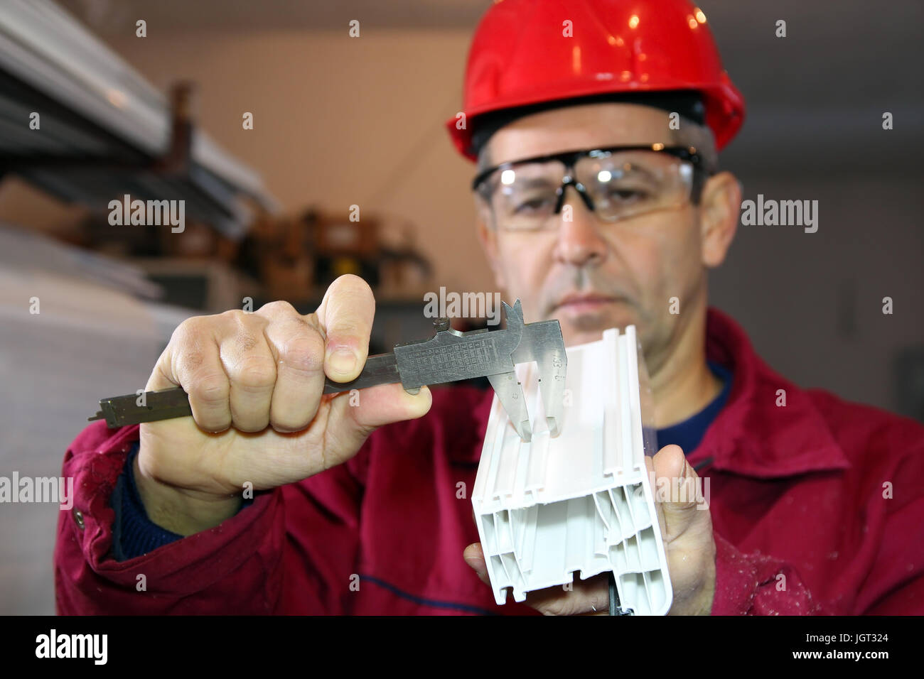 Mechanische Techniker messen mit Bremssattel in Werkstatt für die Herstellung von PVC-Fenstern. Stockfoto