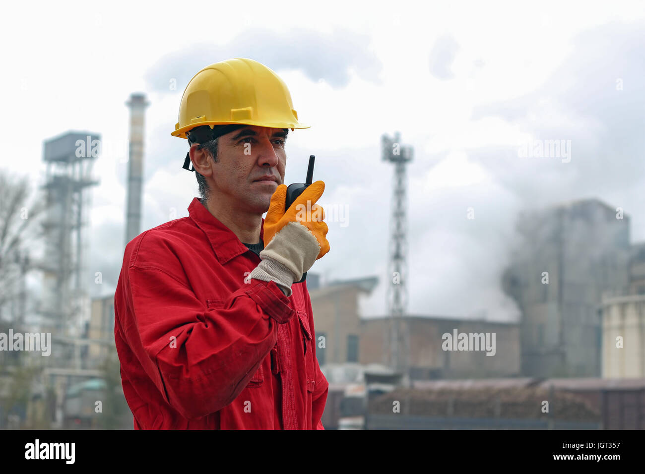 Industriearbeiter in Zuckerfabrik. Ein Portrait eines Arbeitnehmers im roten Overall und gelben Helm. Stockfoto