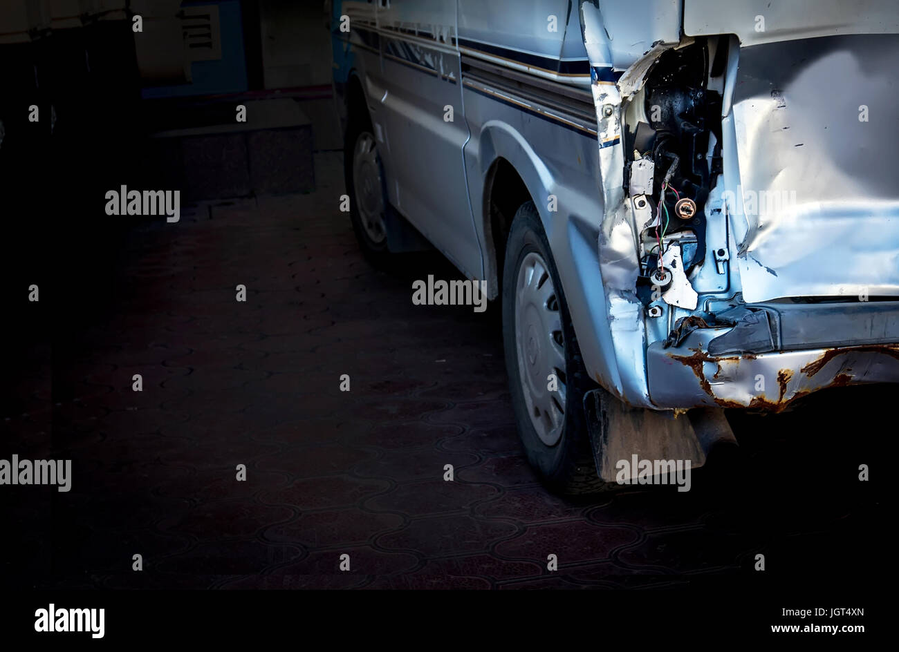 Ein Auto mit einem defekten Scheinwerfer und Rost in der Garage auf einem schwarzen Hintergrund mit Platz für text Stockfoto