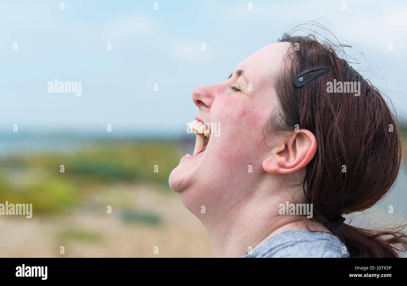 Glückliche junge Frau mit Mund weit offen lachen hysterisch bis es weh tut. Stockfoto