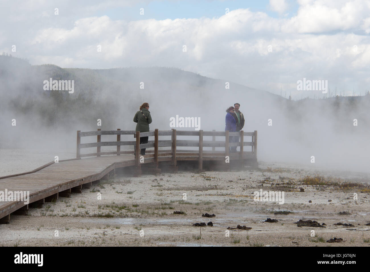 Drei Personen stehen auf der Promenade in der Dampf produziert Rainbow Pool im Black Sand Basin, Upper Geyser Basin, Yellowstone-Nationalpark Stockfoto
