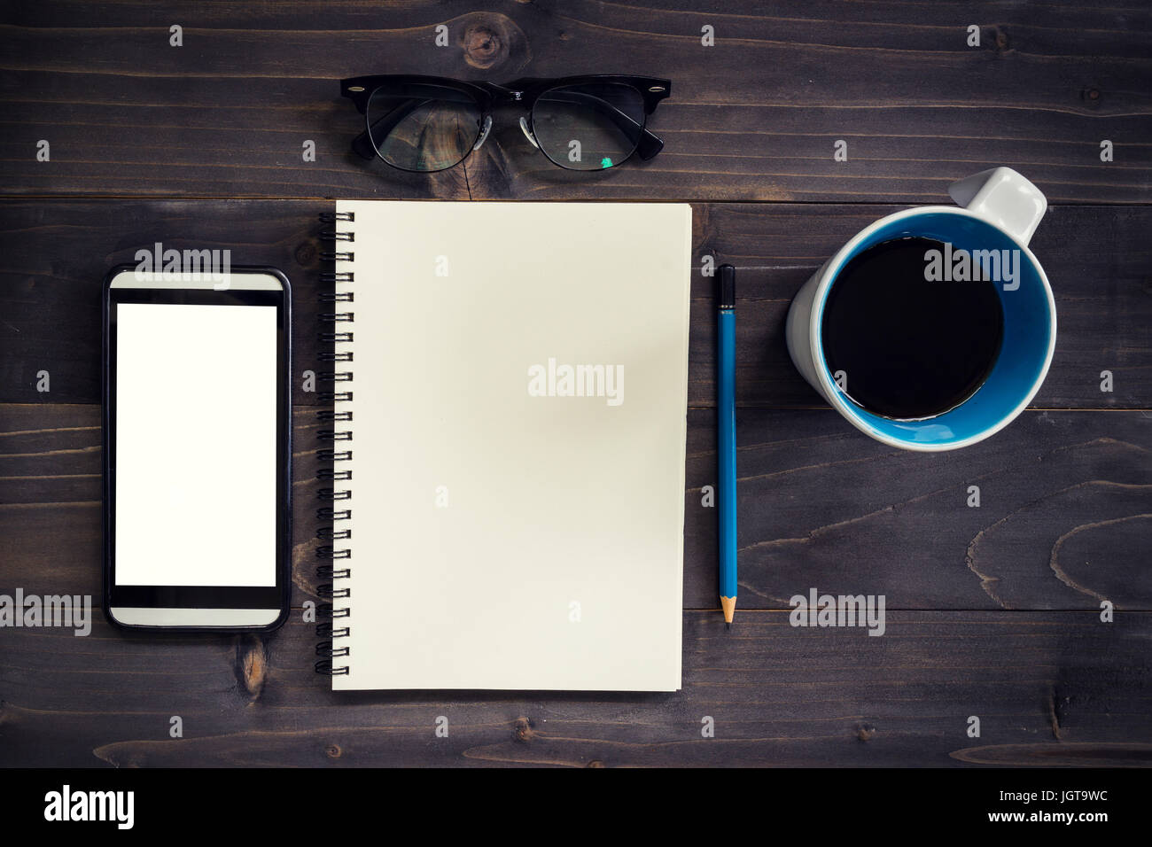 Büro Holz Tisch mit leeren Notizblock, Bleistift, Brille, Handy und weißen Tasse Kaffee. Stockfoto