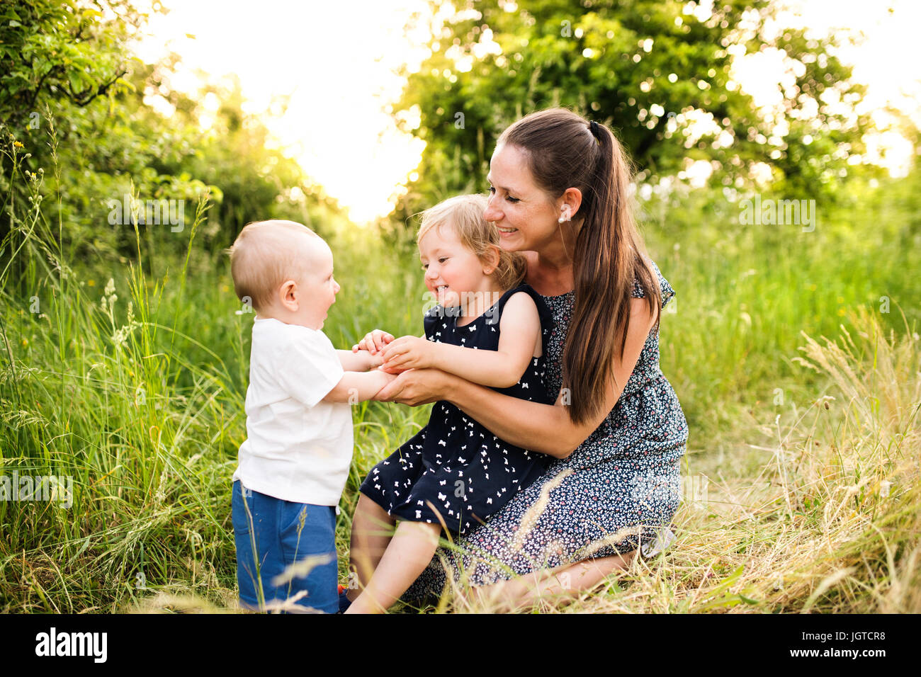 Junge Mutter mit kleinen Kindern im sonnigen Sommer-Natur Stockfoto
