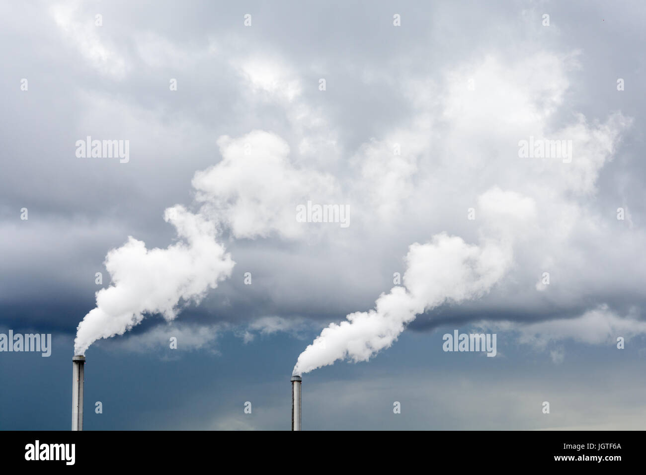 Industrielle Rauchentwicklung aus Fabrikschlot unter Gewitterhimmel. Stockfoto