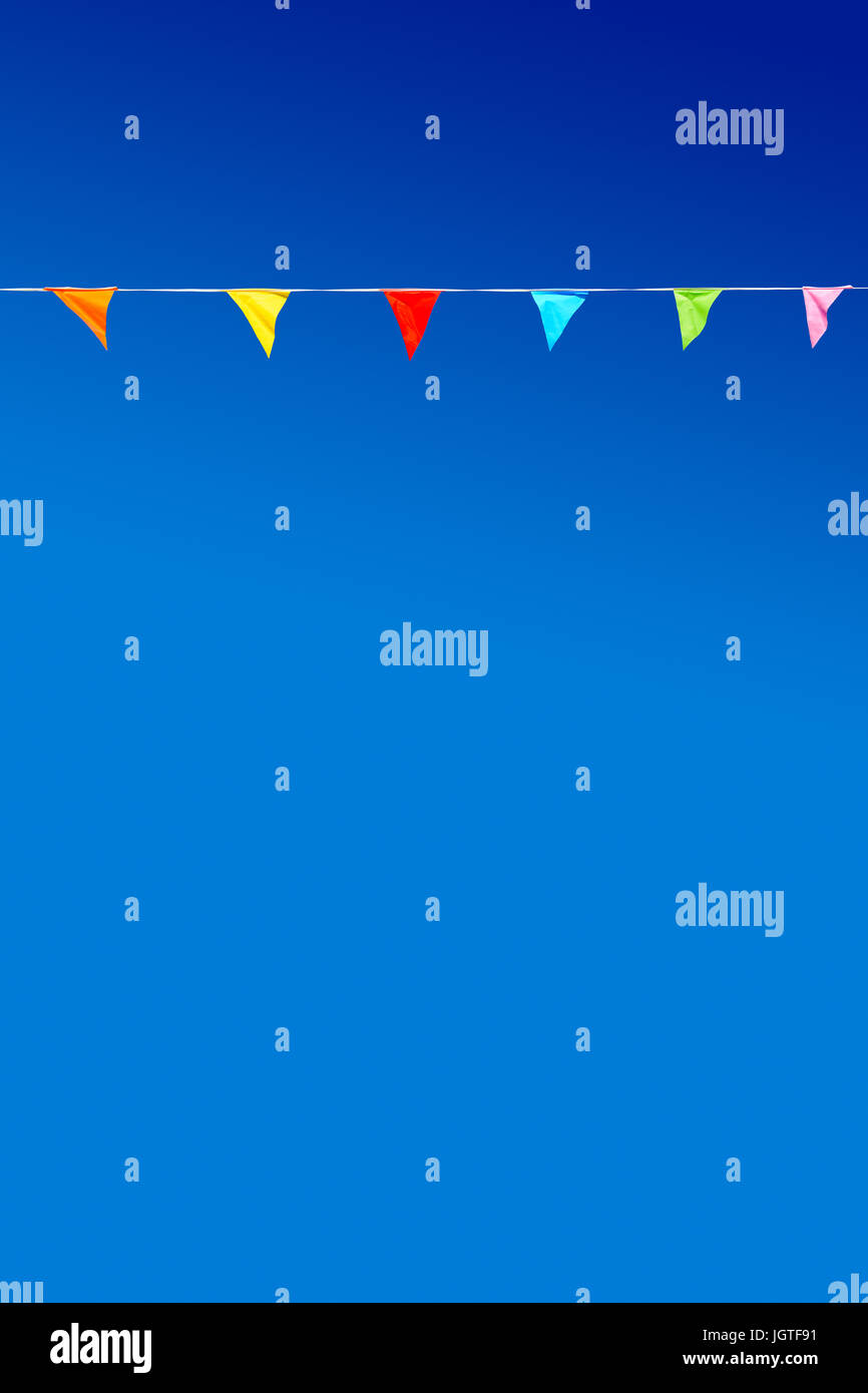 Bunting mit sechs mehrfarbigen dreieckigen Partyfahnen gegen blauen Himmel. Stockfoto