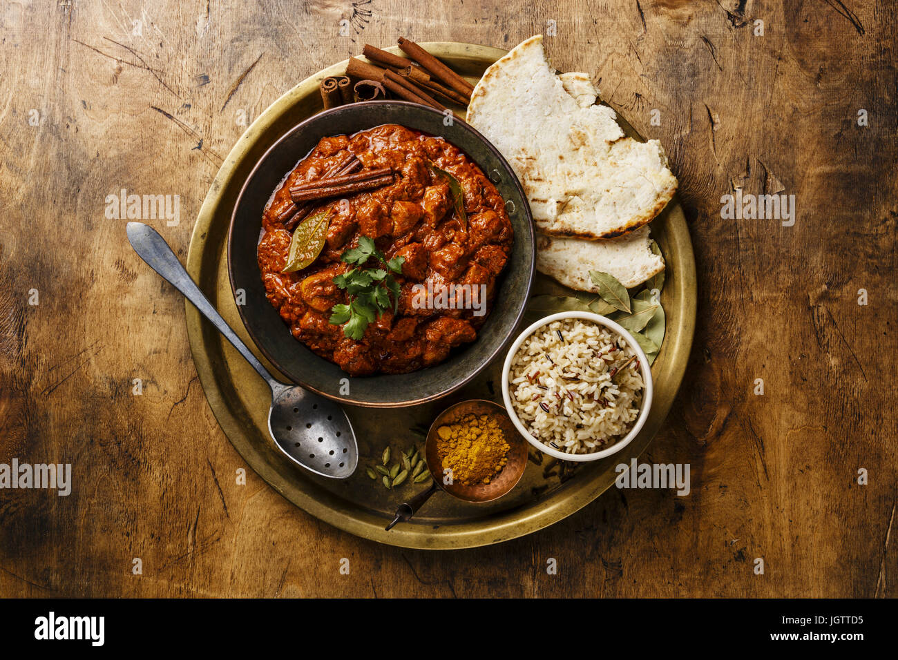 Chicken Tikka Masala-würzigen Curry-Fleisch-essen in Kupfer Pfanne mit Reis und Naan Brot auf hölzernen Hintergrund Stockfoto