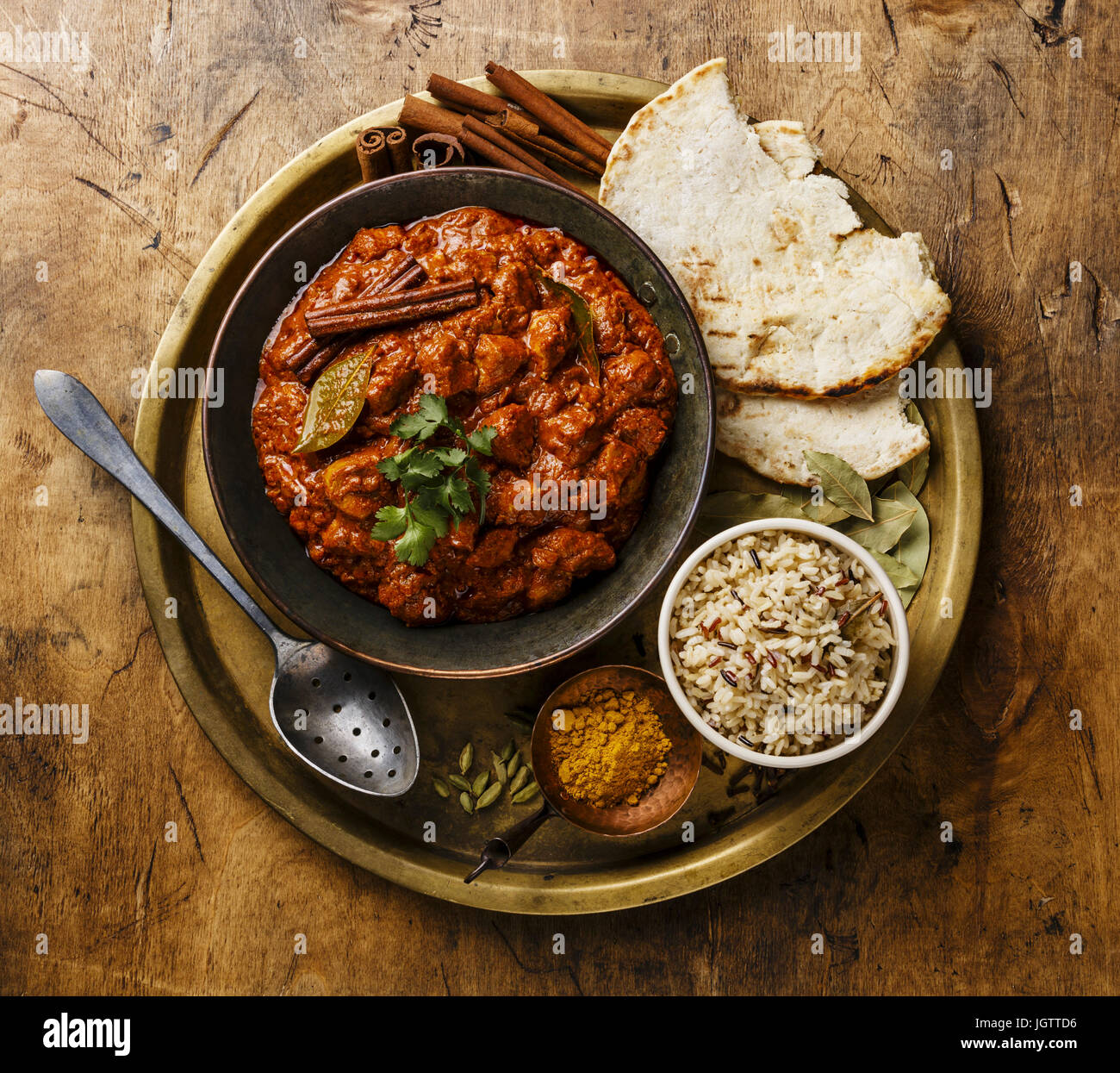 Chicken Tikka Masala-würzigen Curry-Fleisch-essen in Kupfer Pfanne mit Reis und Naan Brot auf hölzernen Hintergrund Stockfoto
