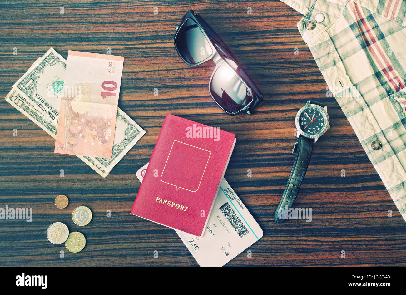 Crossen Bild des männlichen Reise Accessoires Sonnenbrillen, Pass, Geld, Shirt, Uhr und Bordkarte gelegt auf Holztisch in der Abendsonne auf einem Stockfoto