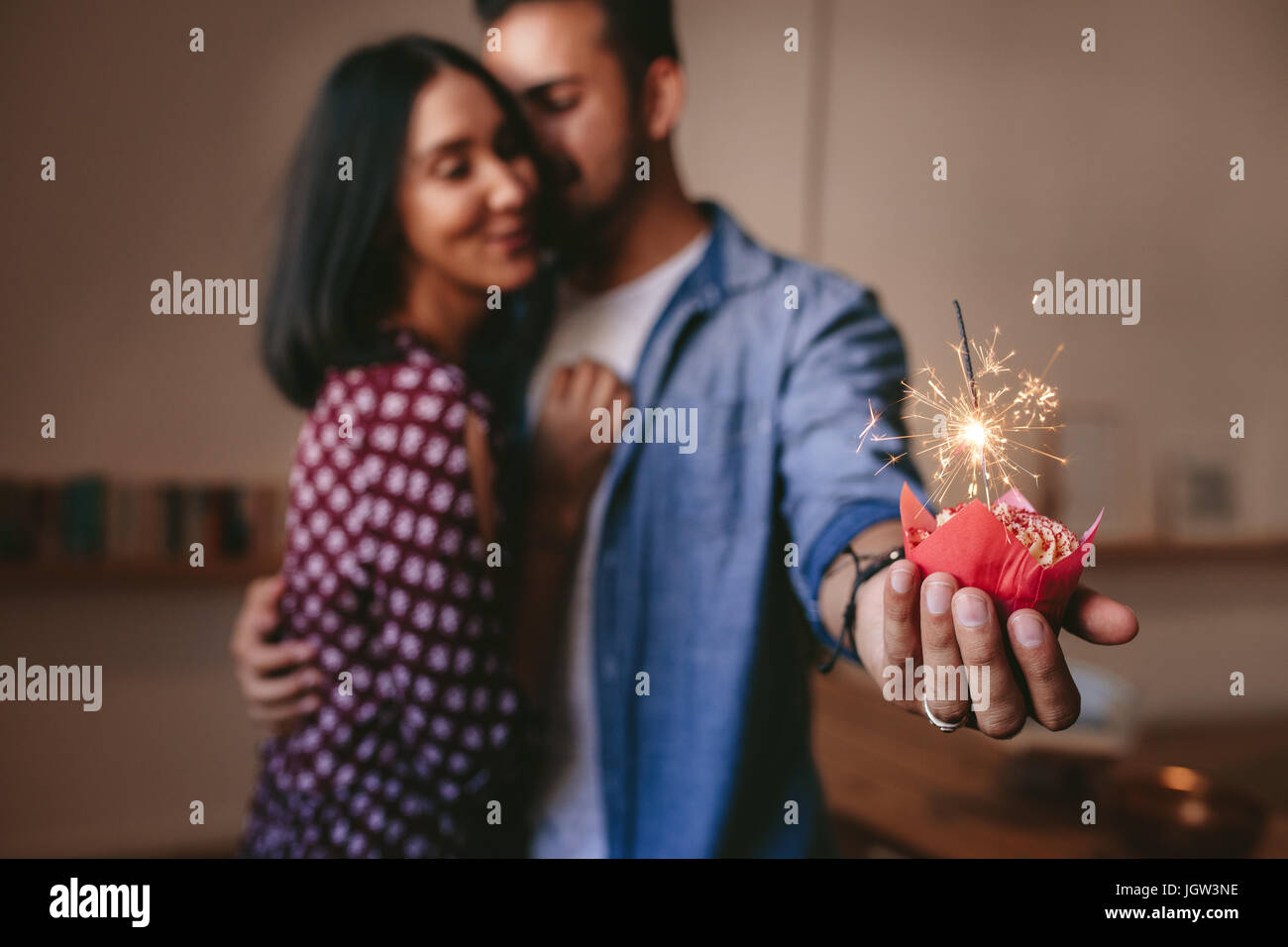 Romantische junges Paar feiert ihr Jubiläum mit Tasse Kuchen. Junger Mann und Frau umarmt mit Tasse Kuchen. Stockfoto