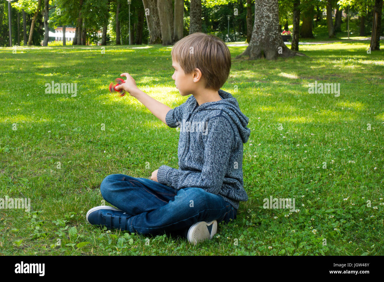 Kind sitzen auf dem Gras und spielt mit Spinner Stockfoto