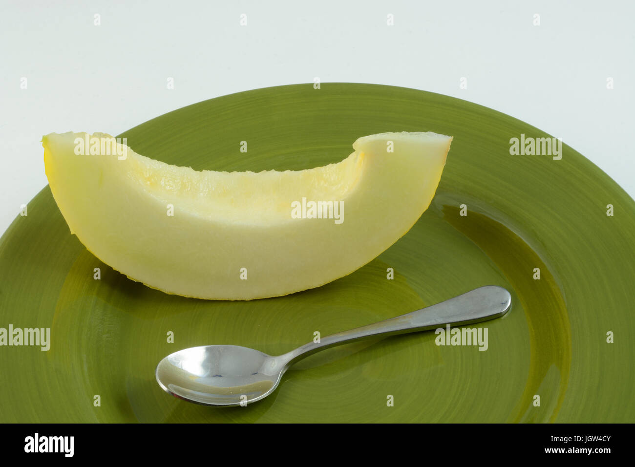 Nahaufnahme eines Slice von golden Honigtau auf grünem Teller mit Löffel Stockfoto