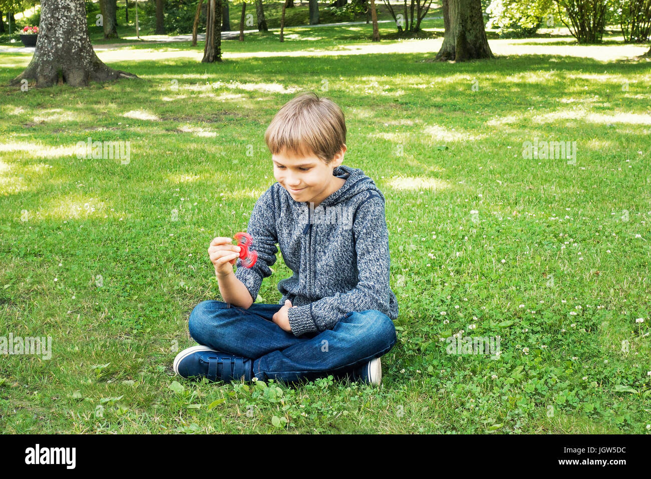 Kind sitzen auf dem Gras und spielt mit Spinner Stockfoto