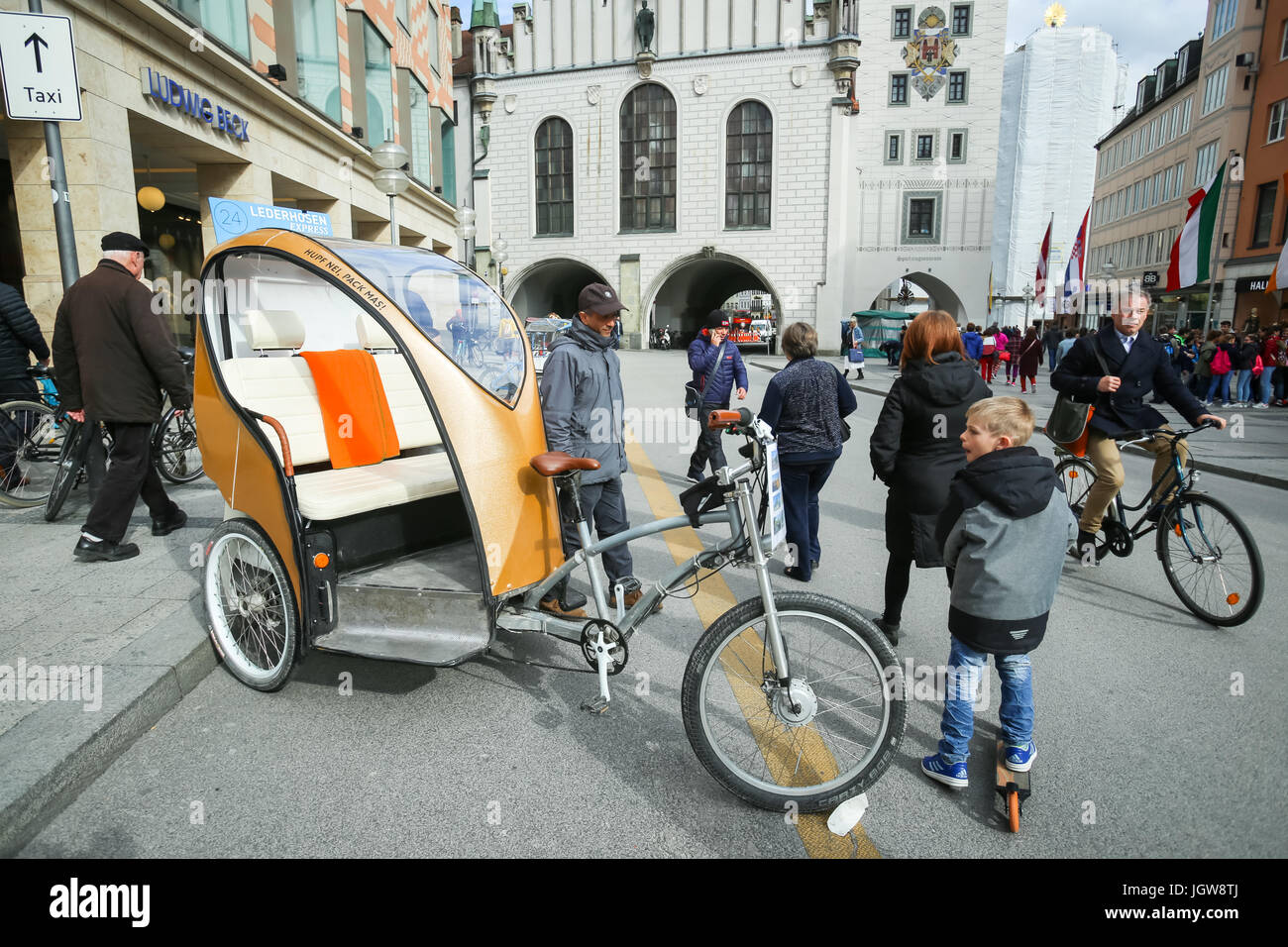 München, Deutschland - 9. Mai 2017: Passanten eine Fahrradrikscha am Marienplatz in München. Stockfoto