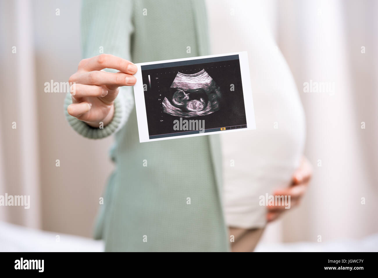 Schwangere Frau hält Ultraschalluntersuchung der Baby und Bauch zu berühren Stockfoto