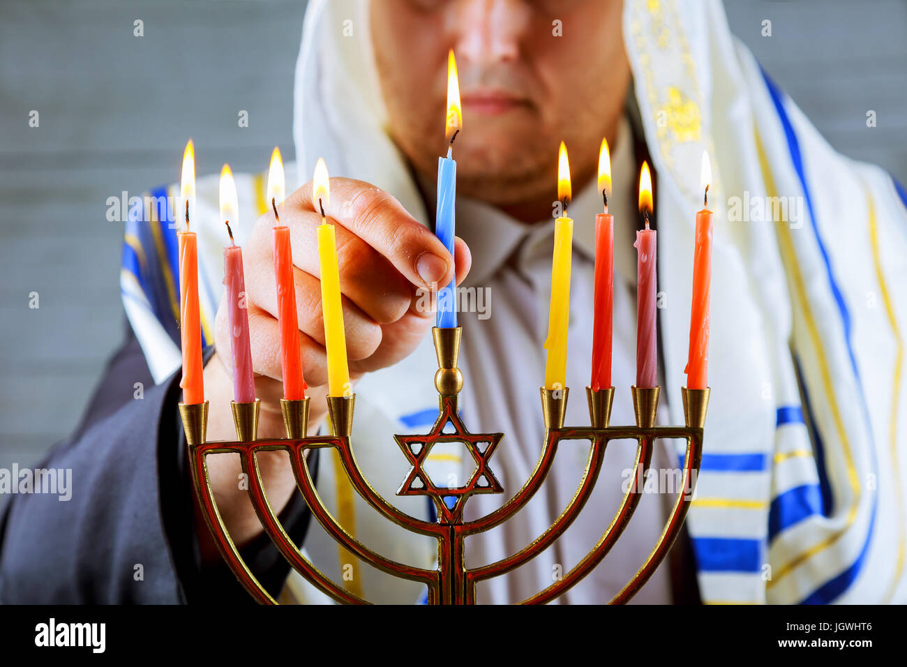 Mann Hand Anzünden von Kerzen in Menora am Tisch serviert für Chanukka Stockfoto