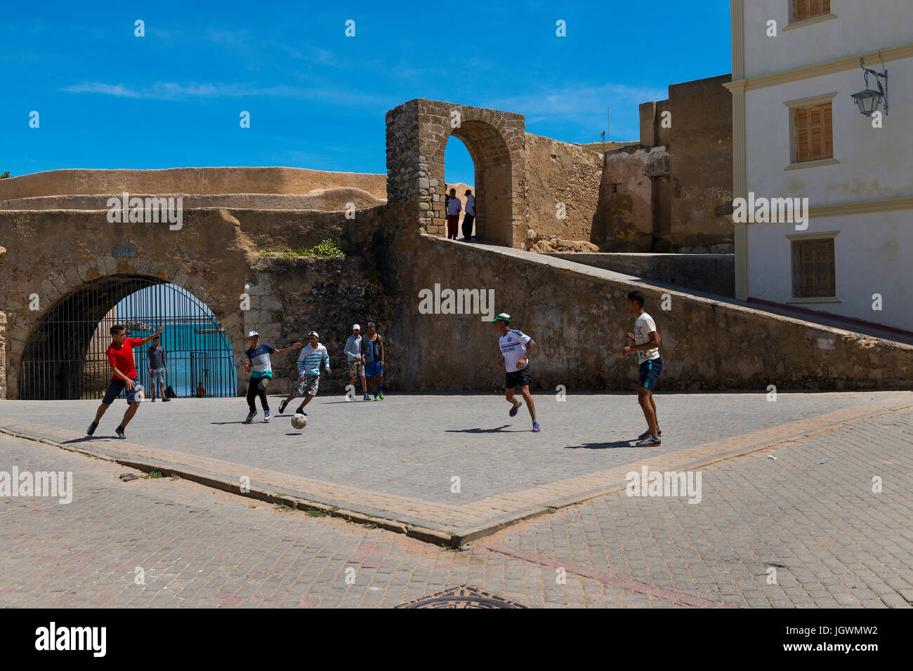 El Jadida, Marokko - 16. April 2016: Junger Mann Fußball spielen auf einem Platz in der Nähe der Mauern der Festung der portugiesischen Stadt (Cite Portugaise) Stockfoto