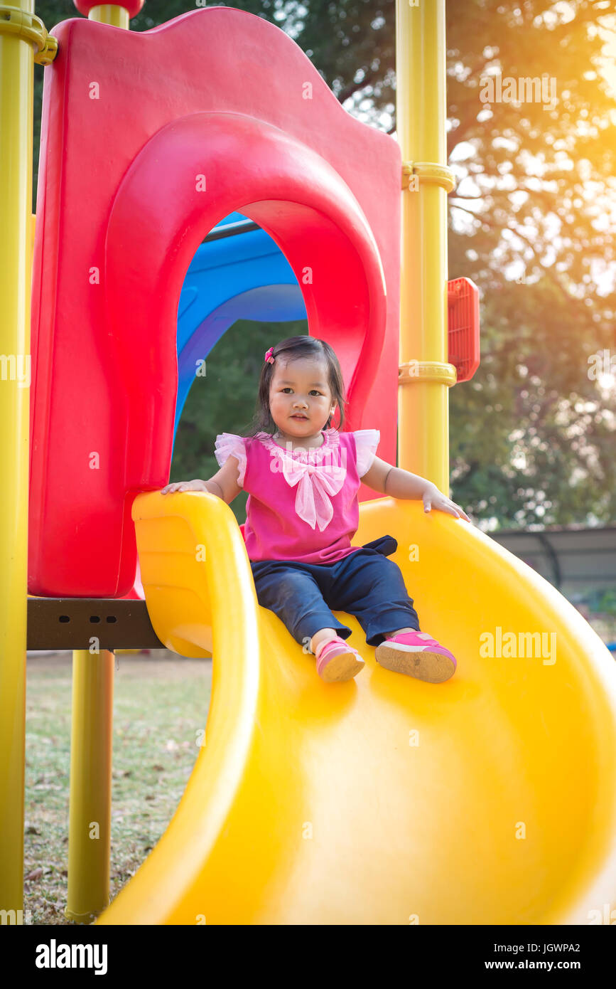 Kleinkind Mädchen spielen auf einer Folie am Kinderspielplatz. Stockfoto