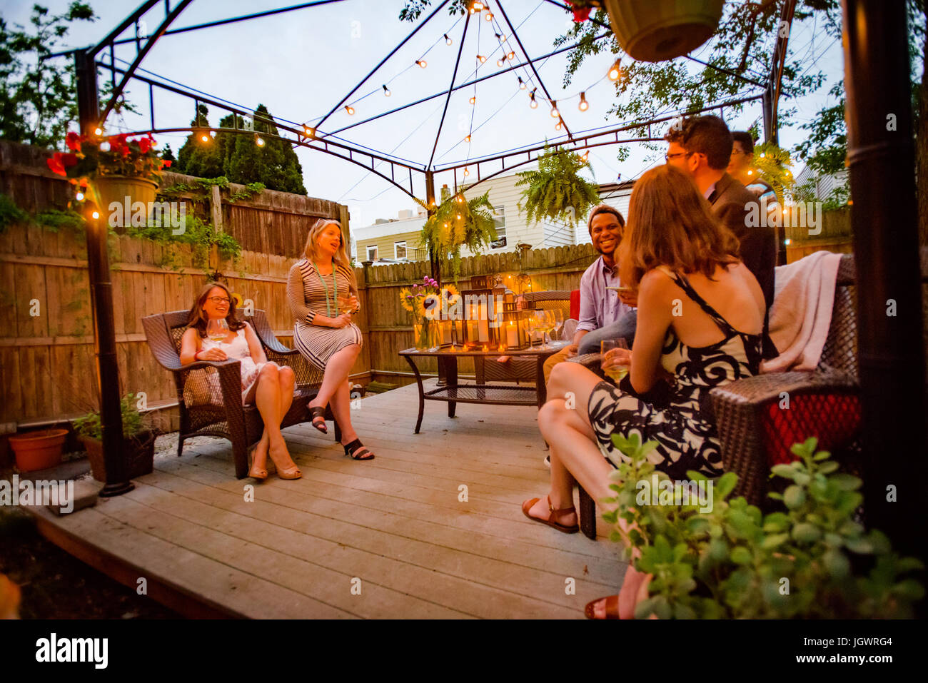 Gruppe von Menschen auf Gartenparty, sitzen auf der Terrasse, im Gespräch Stockfoto