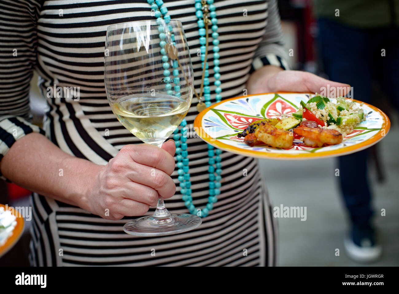 Frau mit Glas Wein und Teller mit Essen, Mittelteil Stockfoto