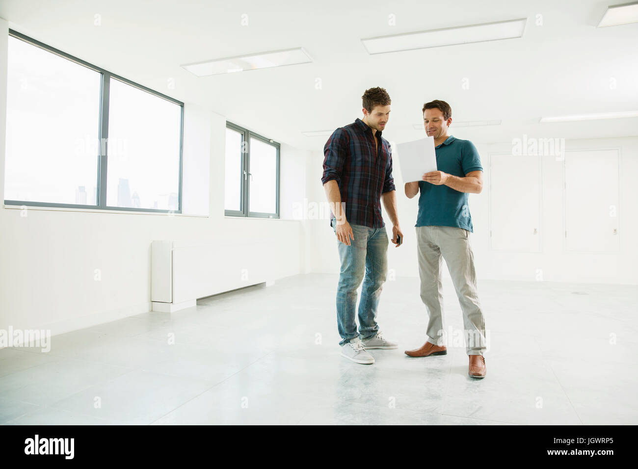 Zwei Männer stehen in leeren Büroflächen, Blick in die digital-Tablette Stockfoto