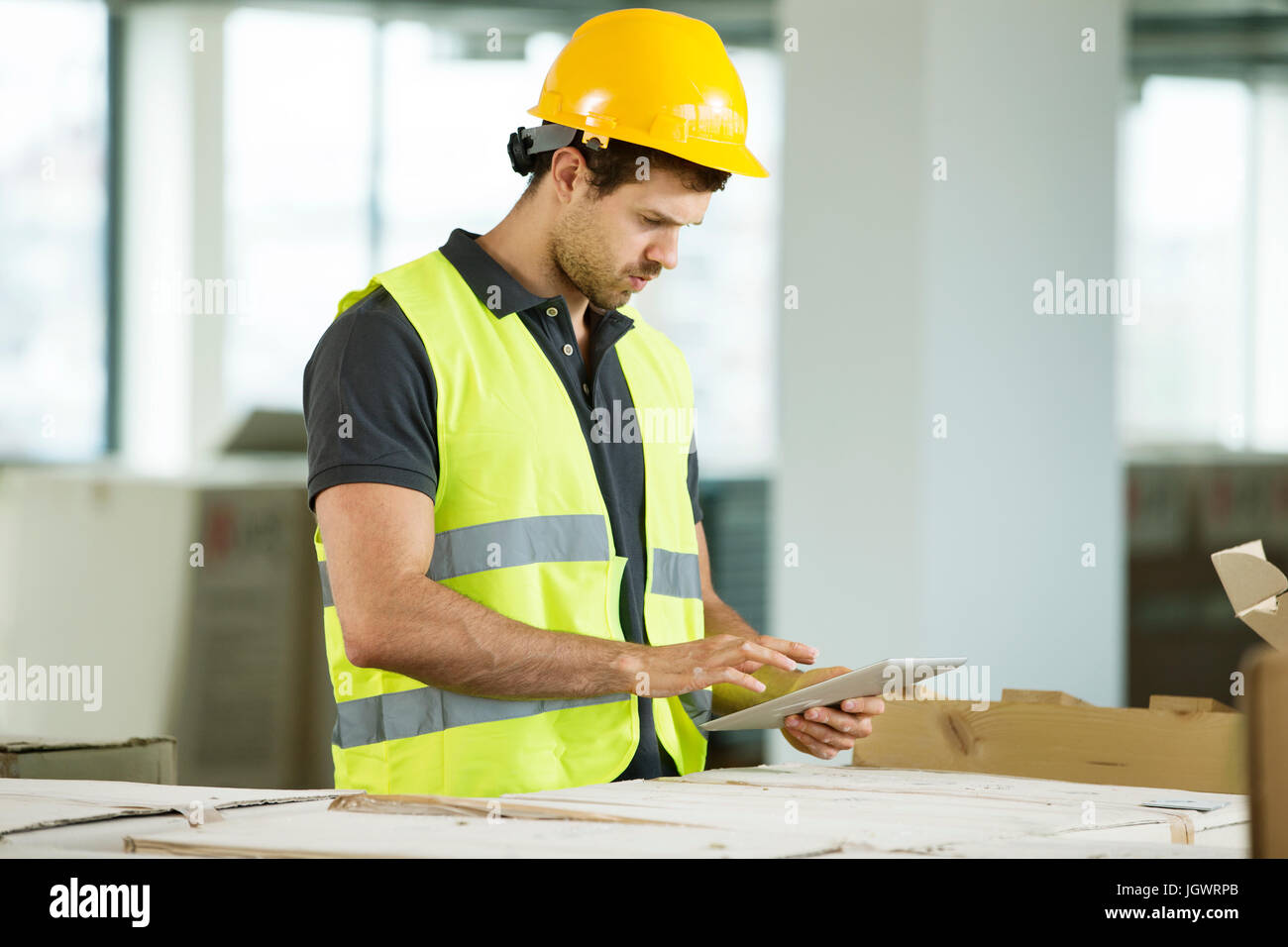 Mann trägt Hallo Vis Weste, im neu errichteten Raum stehen, Blick auf digital-Tablette Stockfoto