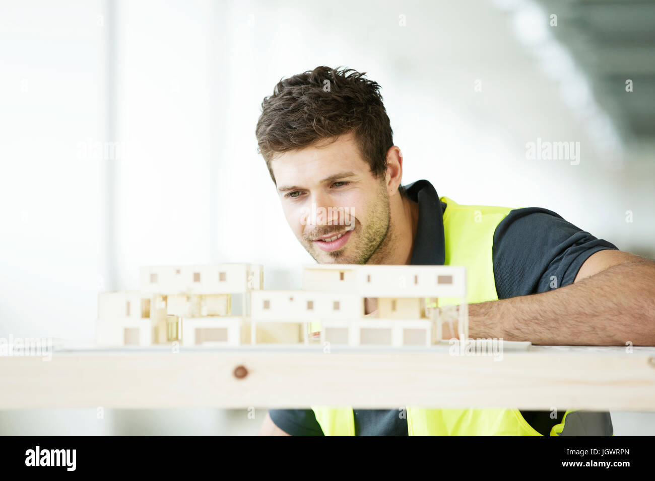 Mann mit Hallo Vis Weste Modell des Gebäudes betrachten Stockfoto