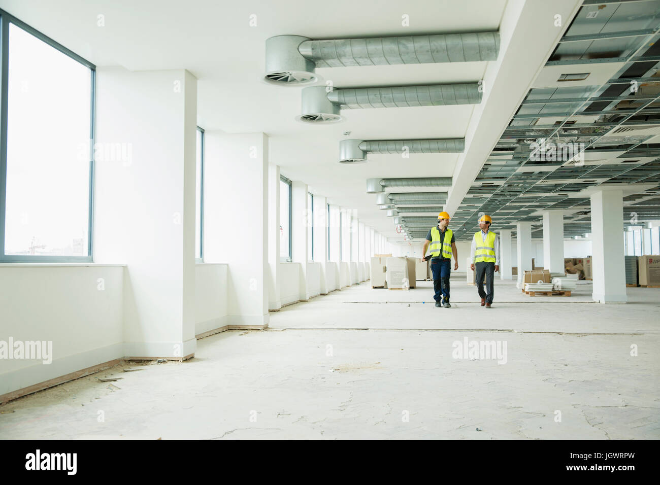 Zwei Arbeiter tragen Hallo Vis Westen, zu Fuß durch neu Büroflächen gebaut Stockfoto