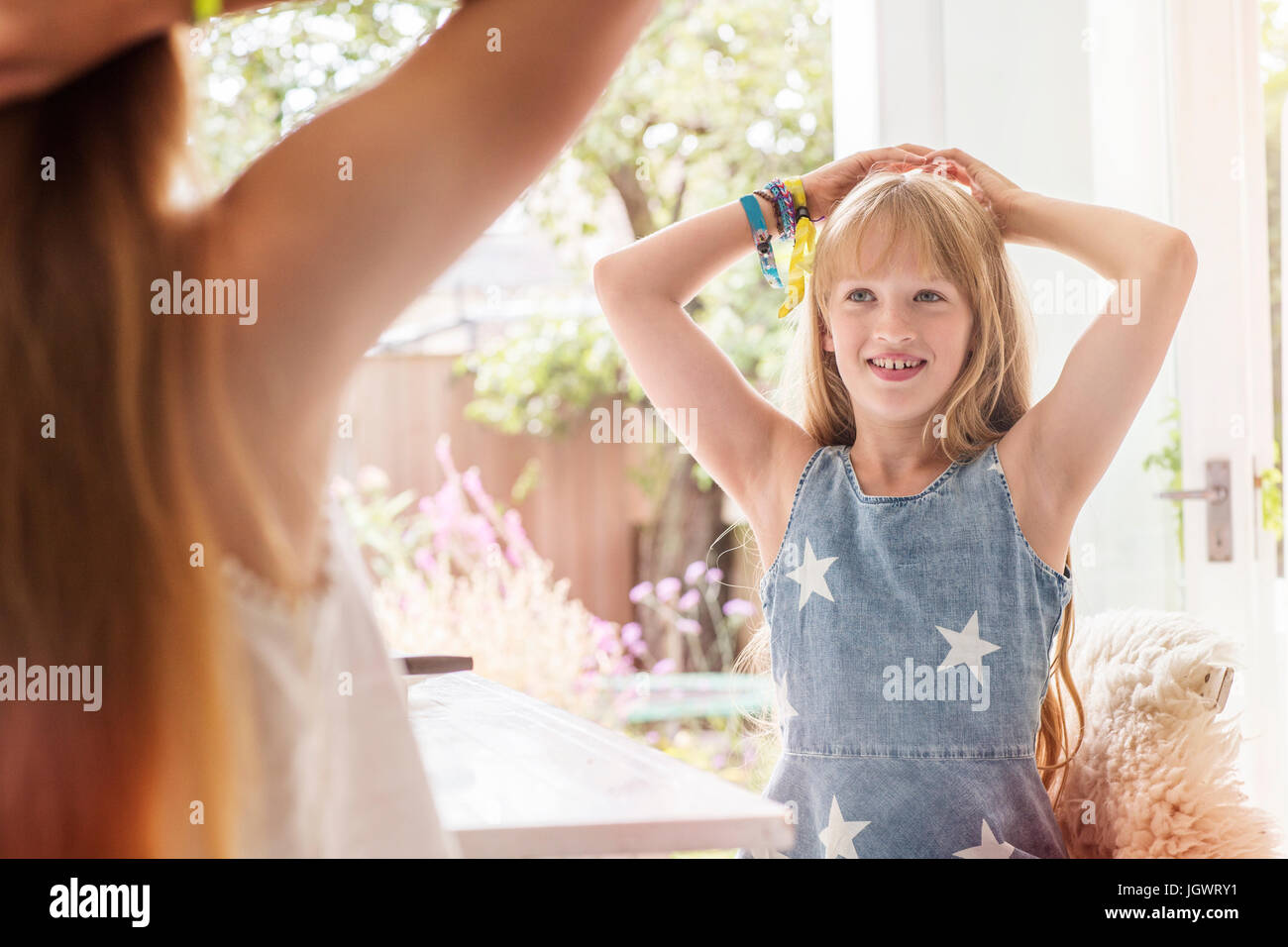 Mädchen mit Händen hinter dem Kopf lächelnd, Schwester kopieren Stockfoto