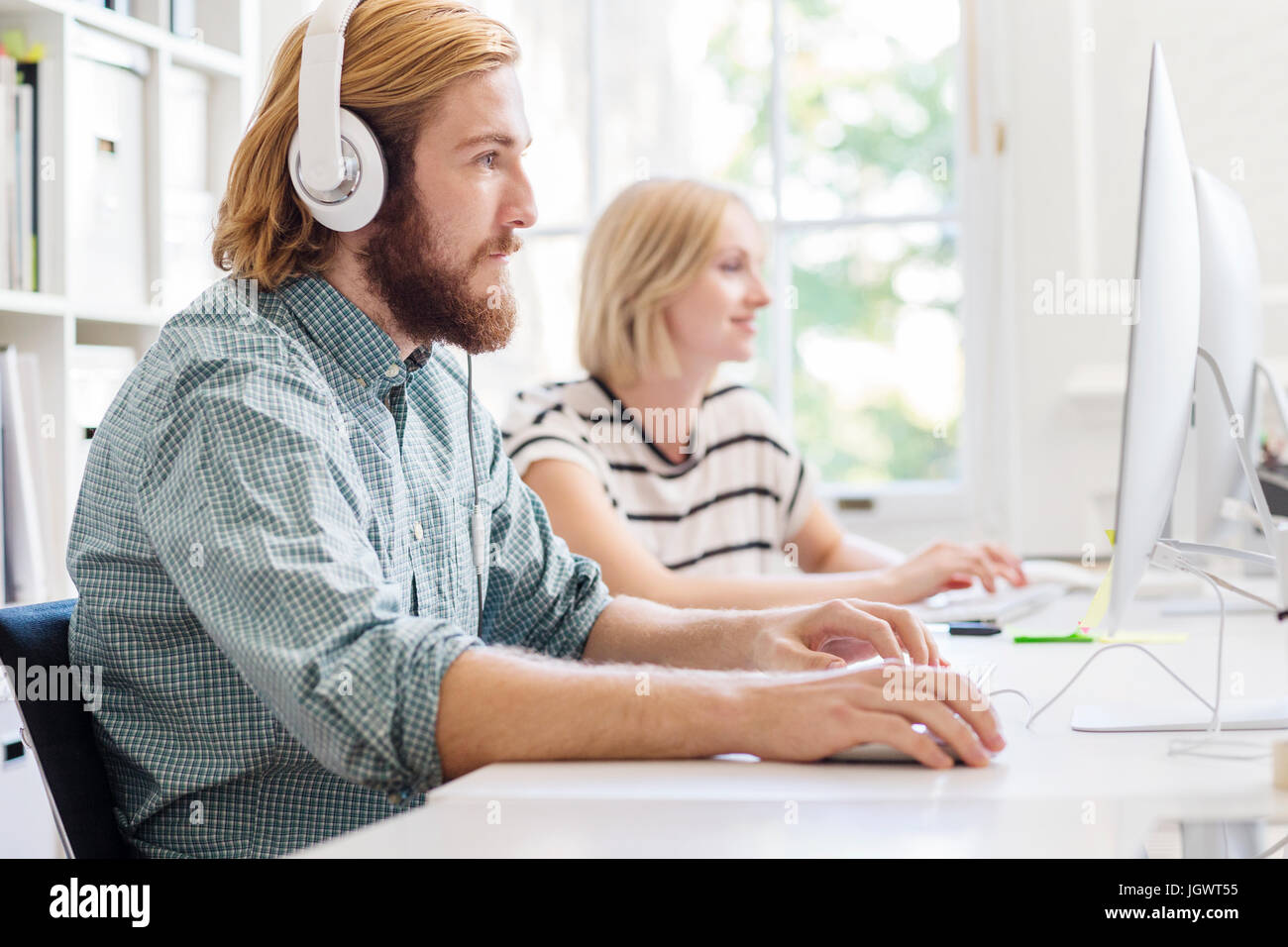 Männliche und weibliche Designer Kopfhörer hören und Schreiben an Kreativstudio Schreibtisch Stockfoto