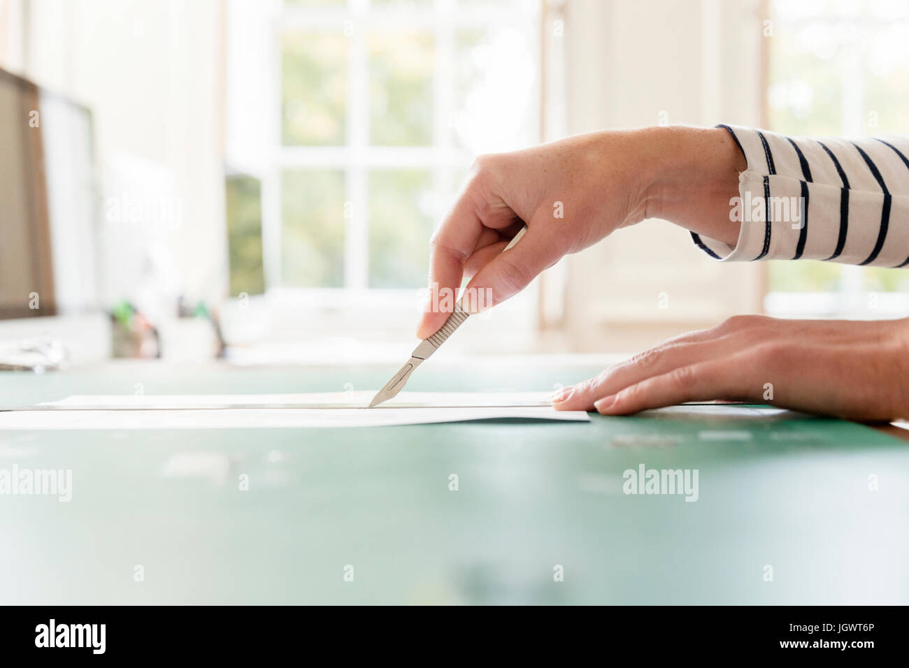 Hand des weiblichen Designer Schneiden von Papier mit Skalpell im Kreativstudio Stockfoto