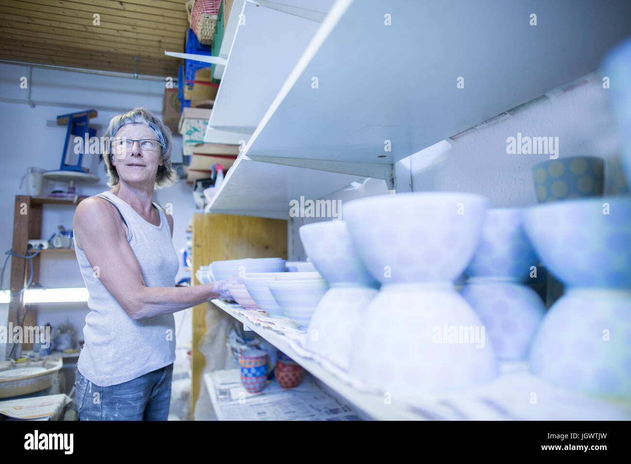Senior Frau in der Töpferwerkstatt, indem Schale auf Regal Stockfoto
