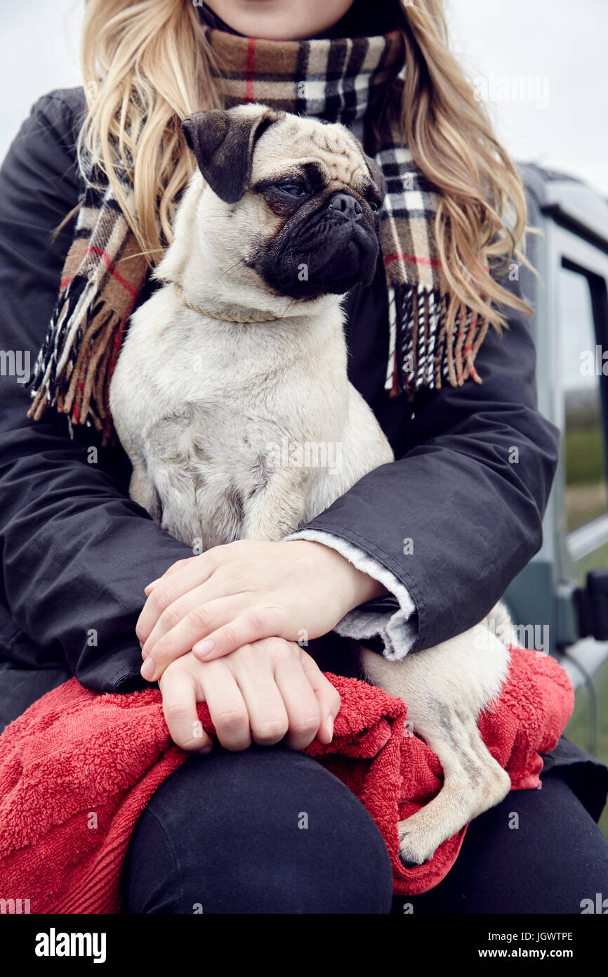 Mittleren Bereich der jungen Frau auf Geländewagen mit Hund auf Schoß sitzen Stockfoto