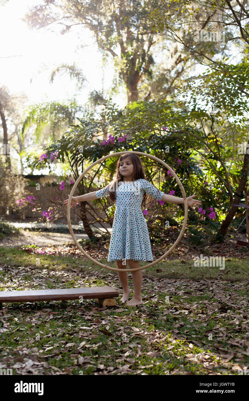 Mädchen spielen mit Hula-Hoop im schattigen Garten Stockfoto