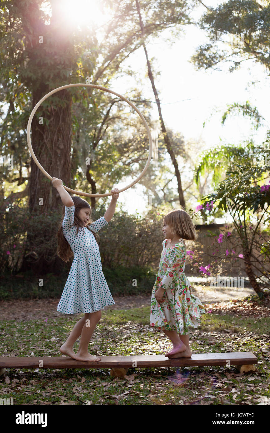 Schwestern spielen mit Hula-Hoop im schattigen Garten Stockfoto