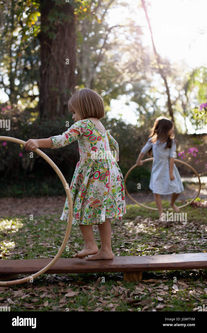 Schwestern spielen mit Kunststoff Reifen im schattigen Garten Stockfoto