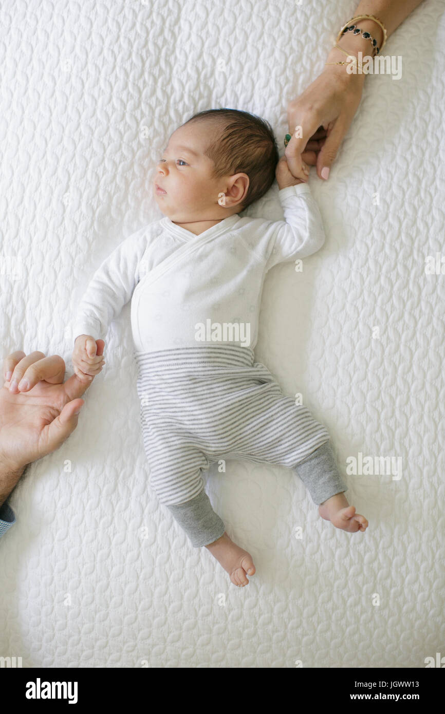 Baby Junge liegend auf dem Bett, Mutter und Vater des Babys Händchen, Draufsicht Stockfoto