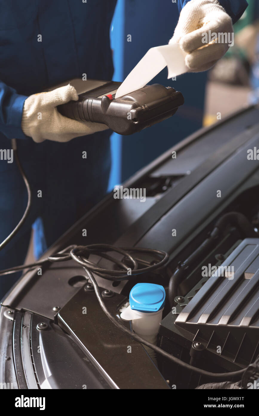 Präzise Messungen. Qualifizierten clever engagierten Kundendiensttechniker mit professionellen Kennzeichen bis zum Motor für die Überprüfung ihrer Leistungsdaten Verdrahtung Stockfoto