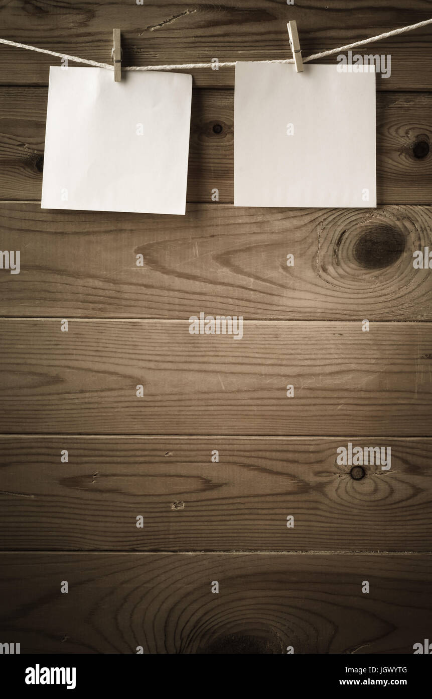 Zwei Quadrate von leeres Papier, gekoppelt an eine Zeichenfolge Wäscheleine mit Holzbrett Zaun im Hintergrund.  Niedrige Sättigung und Vignette gibt ein Retro oder vi Stockfoto