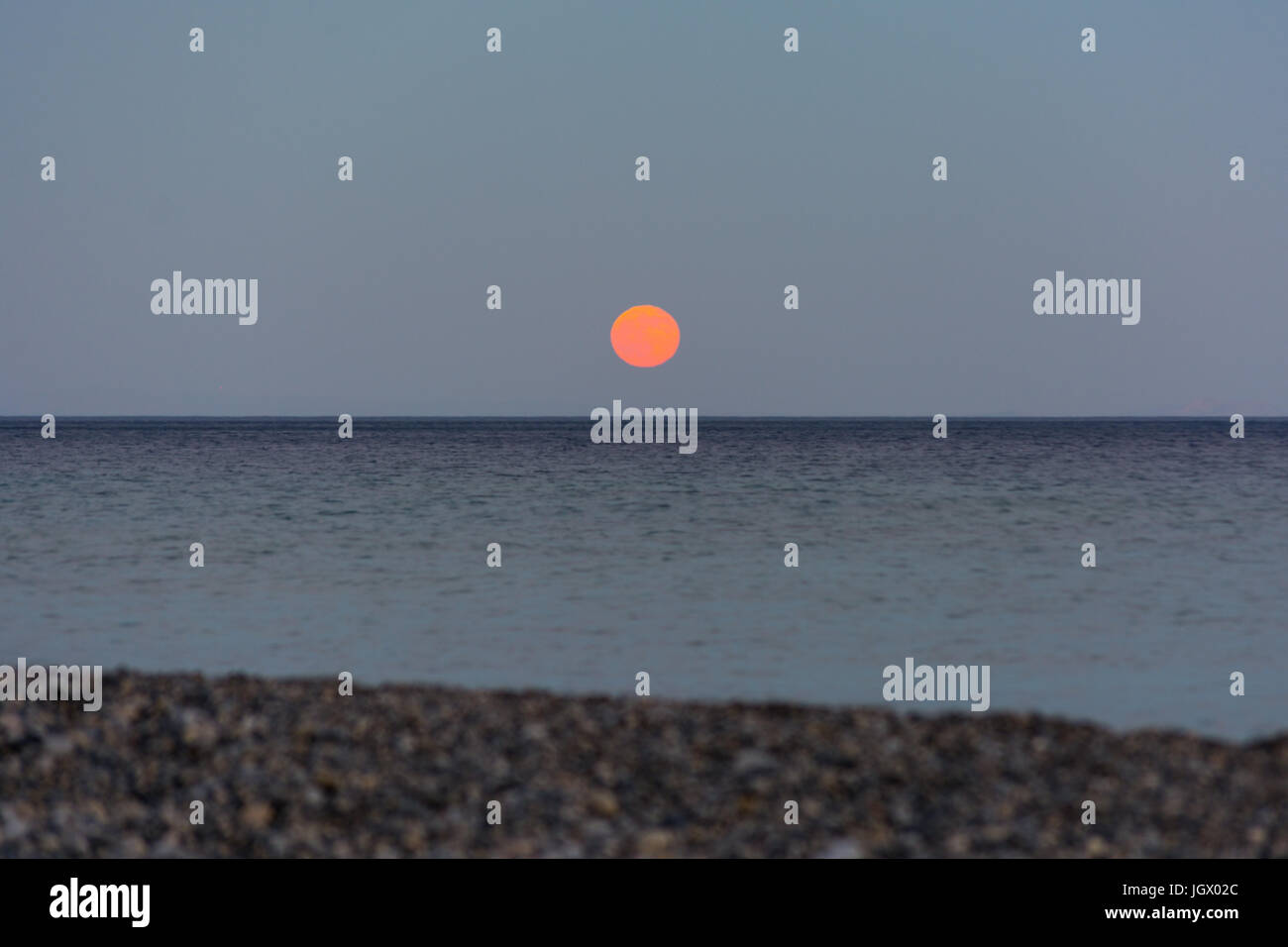 Orangenmond erhebt sich über dem Meeresspiegel mit Kopierraum Stockfoto