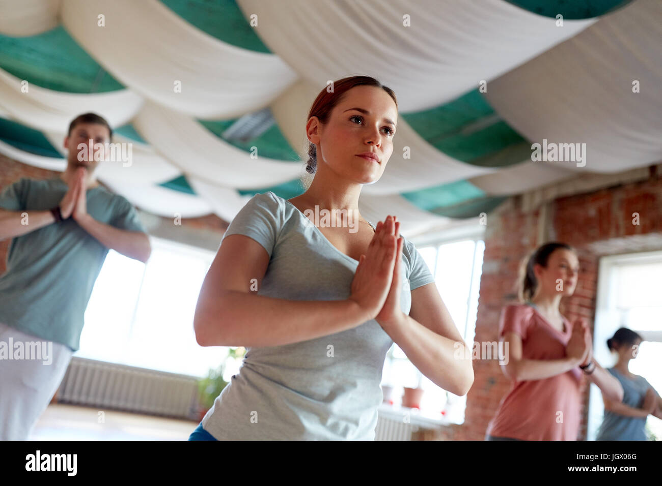 Gruppe von Menschen, die Yoga die Baumhaltung im Studio Stockfoto