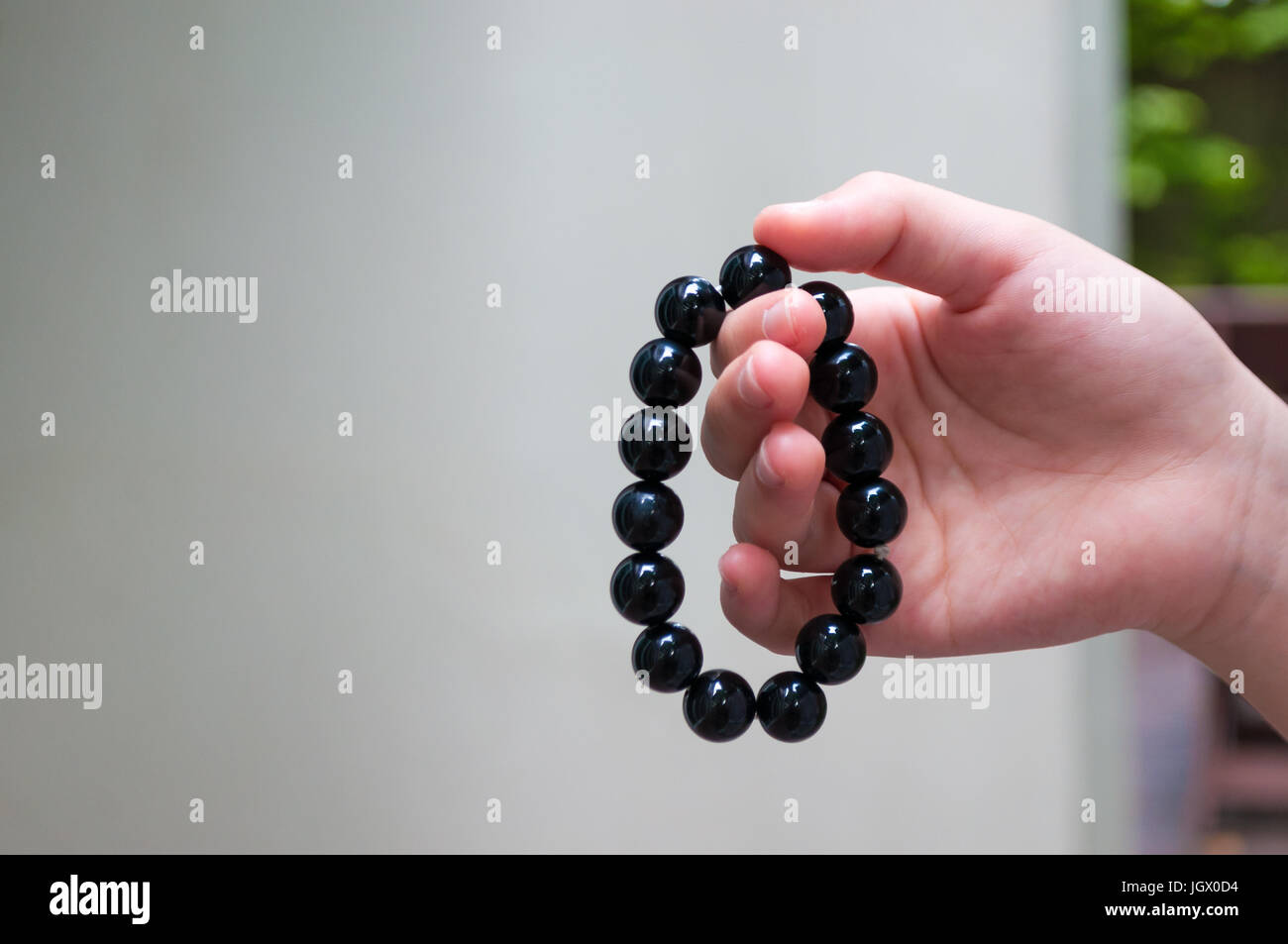 Schwarze Perlen Armband in Mädchen Hand. Kann als modische Accessoires verwendet werden, auch als Gebet Perlen, die für die Zählung von Gebeten oder üben Achtsamkeit meditatio Stockfoto