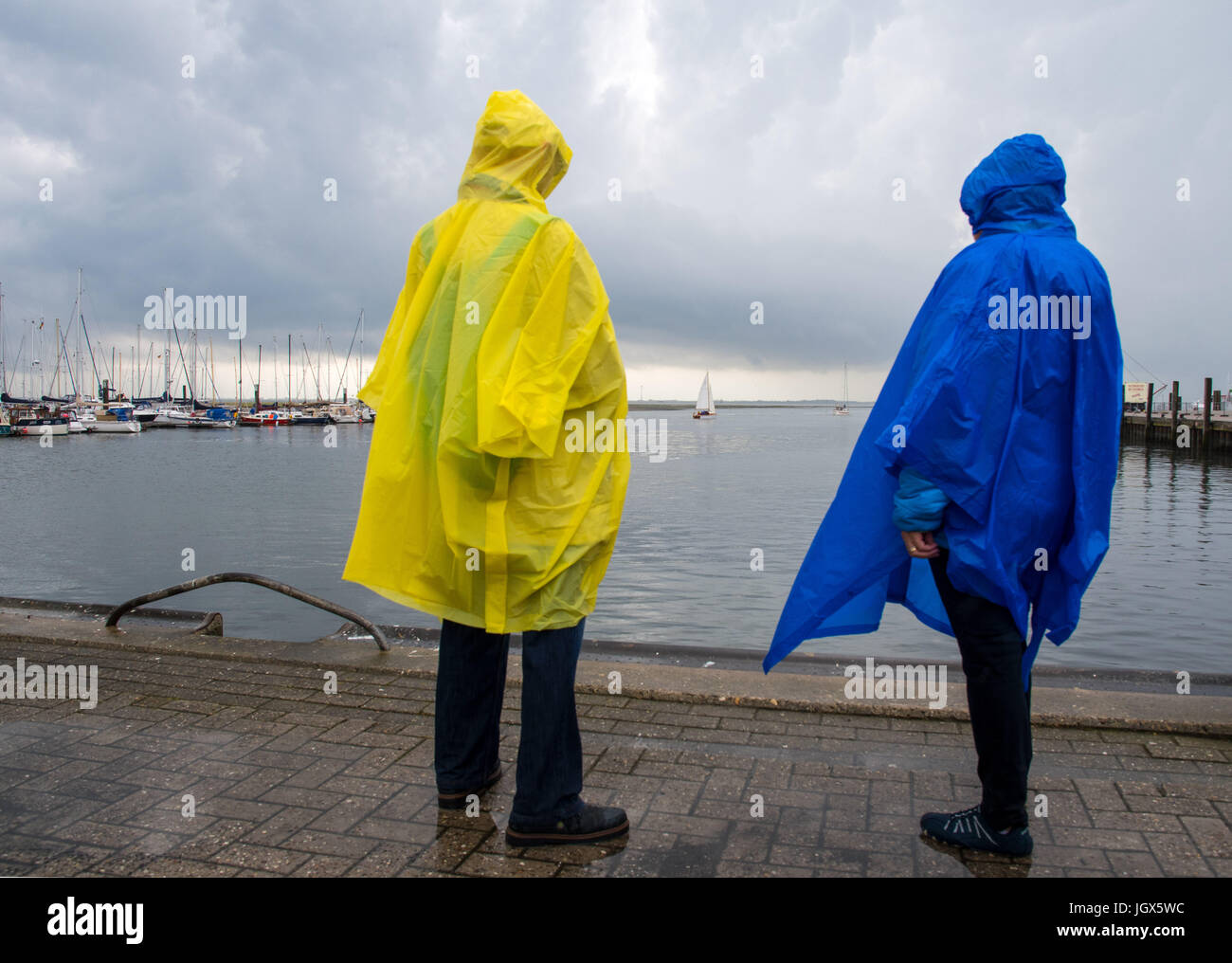 Spiekeroog, Deutschland. 11. Juli 2017. Dpatop - Touristen Regenmäntel an einem regnerischen Tag auf der Nordsee Insel von Spiekeroog, Deutschland, 11. Juli 2017 tragen. Das Wetter auf der Insel bleibt veränderbar. Foto: Ingo Wagner/Dpa/Alamy Live News Stockfoto