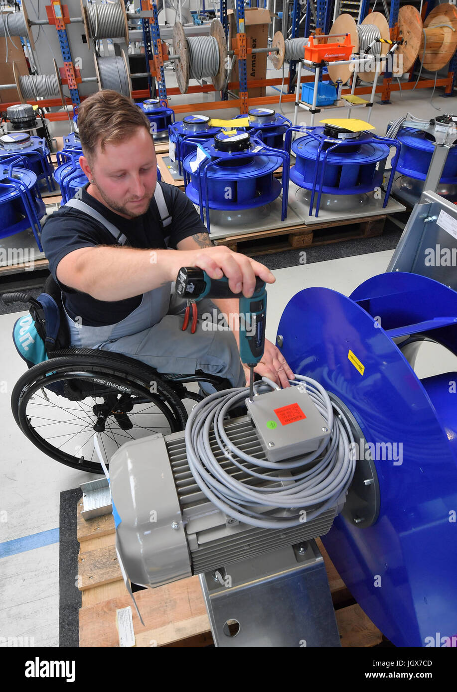 Mitarbeiter Daniel bei der Arbeit in einem Arbeitsbereich für Motorklemmen an DencoHappel Production GmbH in Wurzen, Deutschland, 11. Juli 2017 Schlesinger. Schlesinger benutzt einen Rollstuhl seit einem Autounfall im Jahr 2012. Drei Viertel der ein Jahr nach seinem Unfall zurückgekehrt Schlesinger an den barrierefreien Arbeitsbereich bei der Firma arbeiten. Foto: Hendrik Schmidt/Dpa-Zentralbild/ZB Stockfoto